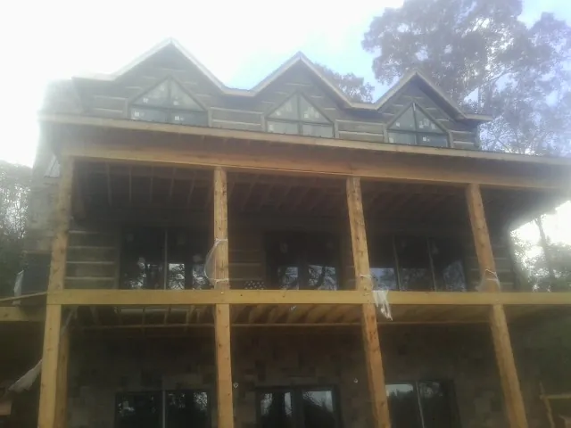 Dormers and porch framing on a large log home under construction — Roof Coating work by our crew in West Alton