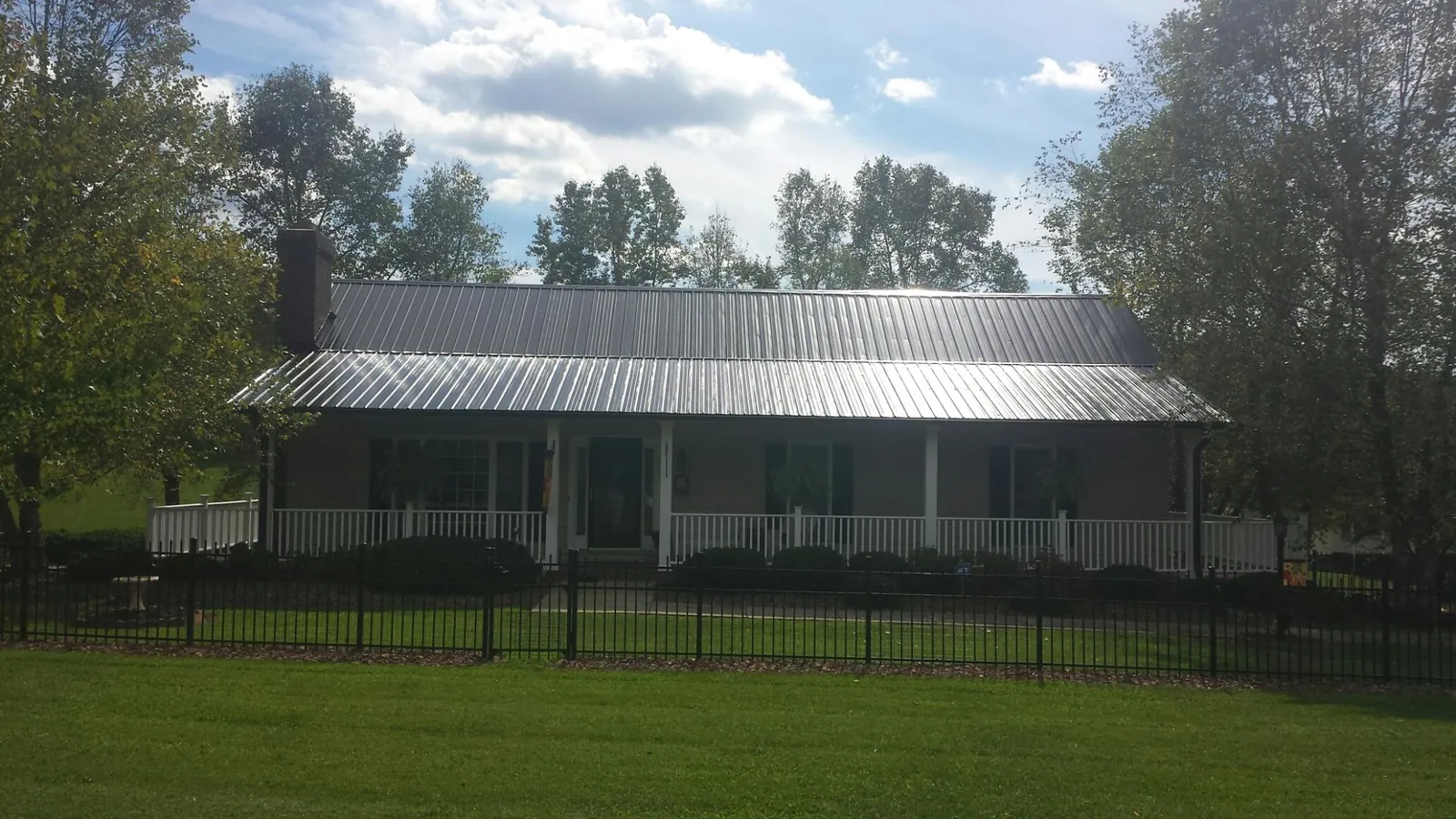 Gray metal roof on a brick ranch with a full width front porch — Gutter Guard Installation work by our crew in West Alton