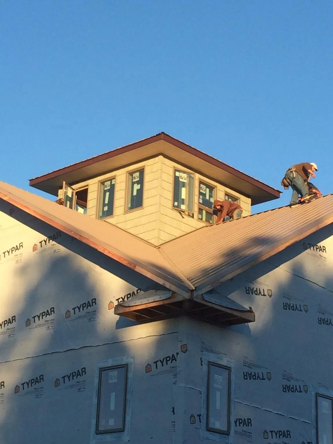 Roofers working around a rooftop cupola on a new metal roof at sunset — Roof Waterproofing in West Alton by Roofing Brothers